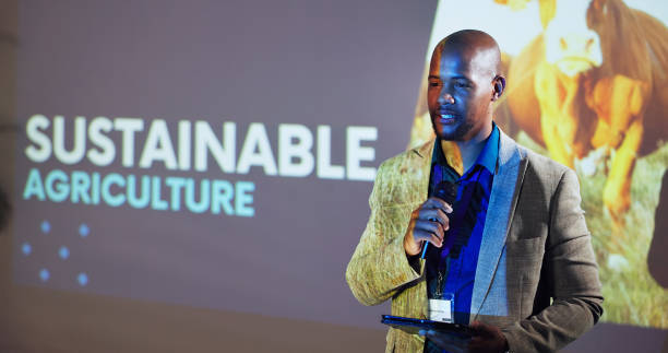 présentation, atelier et homme noir sur une scène pour salon agricole, convention et séminaire. conférencier, public et personne avec tablette lors d’un événement pour l’environnement, la durabilité et l’agriculture - salon agriculture photos et images de collection